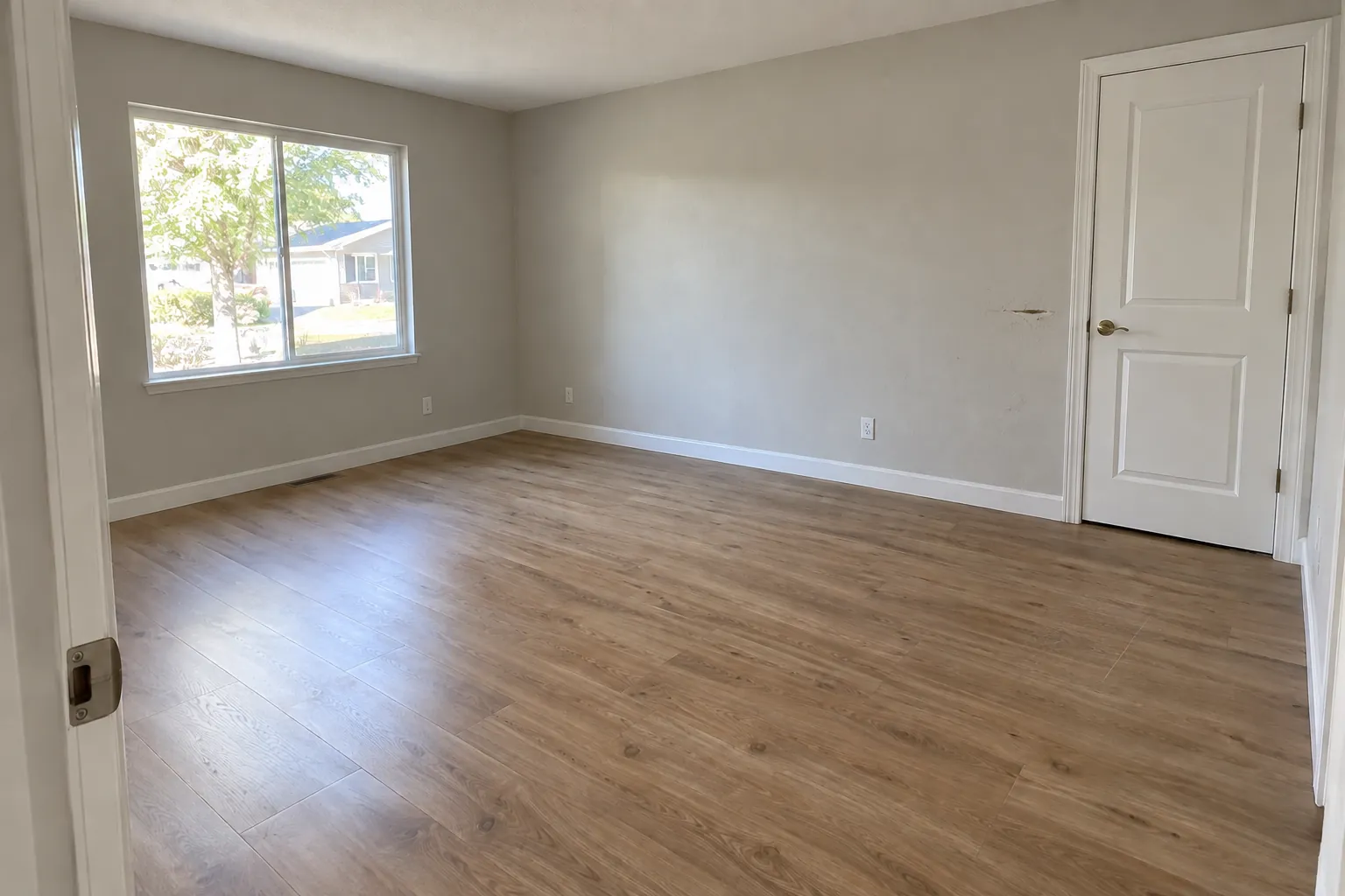 The same living room at move-out: a scuff on the wall beside the bedroom door.